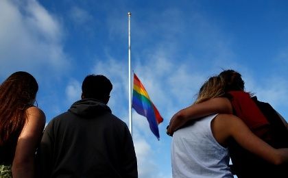 FEELING BESIEGED: Mourners in San Diego, California, gather under an LGBT pride flag at a candlelight vigil in remembrance of victims of the mass shooting in Orlando, Florida. 