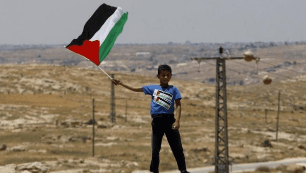 A Palestinian Bedouin boy holds a Palestinian flag during a protest against Jewish settlements in Susya village south of the West Bank city of Hebron June 5, 2015. 