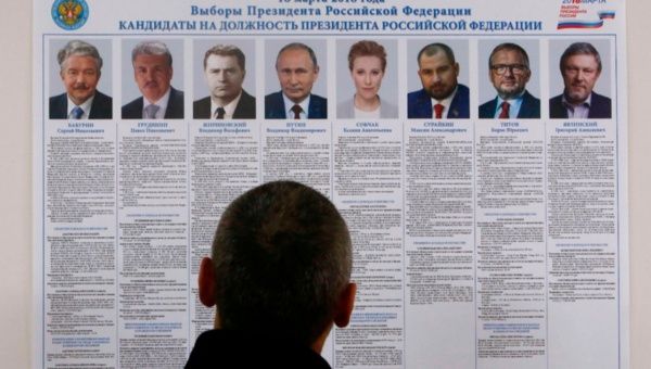 A voter looks through a broadsheet with information about the candidates during the early voting ahead of the March 18 presidential election in a settlement on the Pechora Sea island of Kolguyev in Nenets Autonomous District, Russia February 28, 2018.