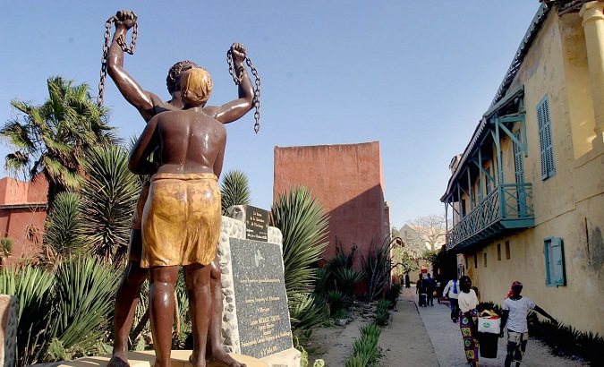 Senegalese women walk past a monument to slavery near the Slave house on Goree island 3km off Dakar, Senegal .