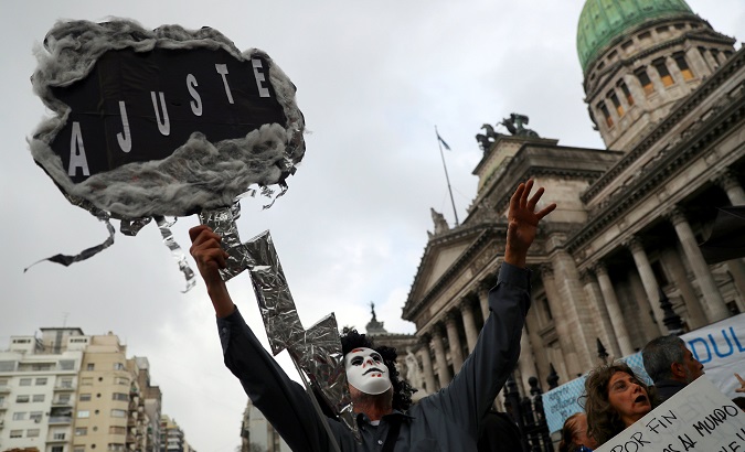 Man in mask holds sign reading 