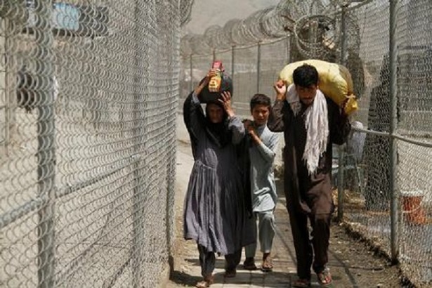 A family coming from Afghanistan walk down a corridor between security fences at the border post in Torkham, Pakistan June 18, 2016.