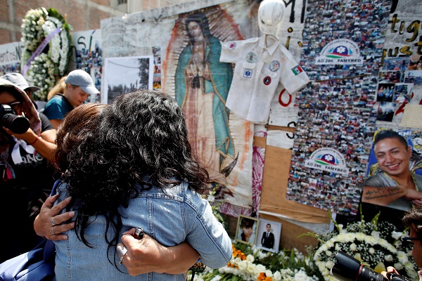 Women react, remembering their relatives who died in a building that collapsed during the earthquake, after the minute of silence to honor the victims.