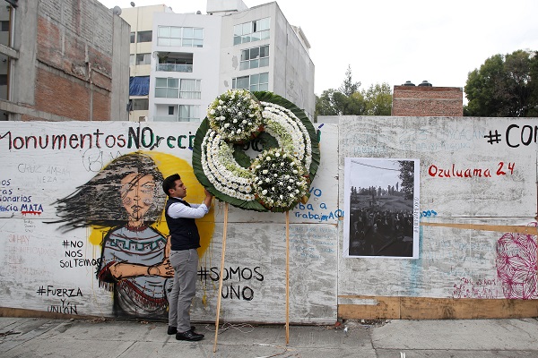 A man places a wreath honoring the victims of a building that collapsed during the earthquake in Mexico City.