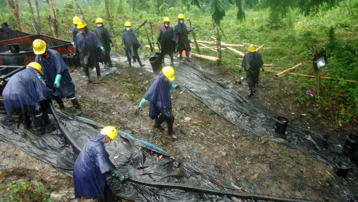 Trabajadores limpian un derrame petrolero en la amazonía peruana.