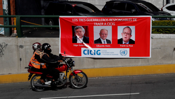 Una moto pasa junto a un cartel que critica a la Comisión Internacional Contra la Impunidad en Guatemala (CICIG).