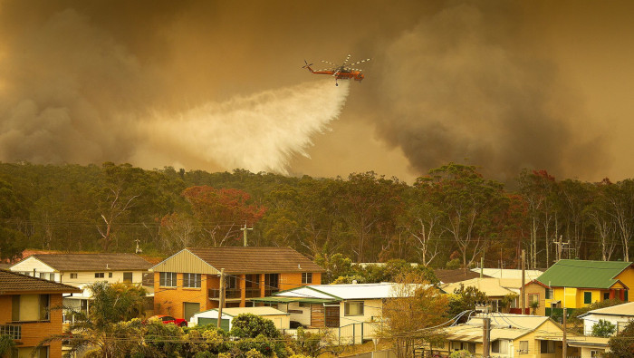 Un helicóptero del Servicio Rural de Bomberos descarga agua sobre los incendios que arrasan los bosques de la ciudad de Harrington (Australia).