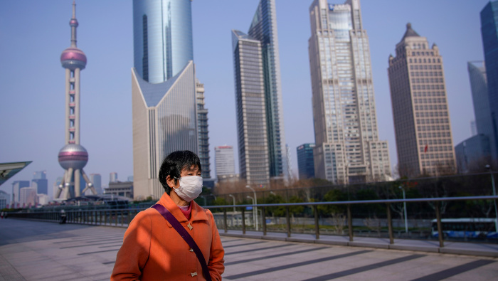 Una mujer con una mascarilla es vista en el distrito financiero de Lujiazui en Pudong, Shanghai, China.