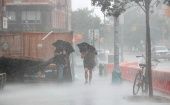 Dos personas caminan bajo el fuerte viento y la lluvia durante la tormenta tropical Isaías en Nueva York.